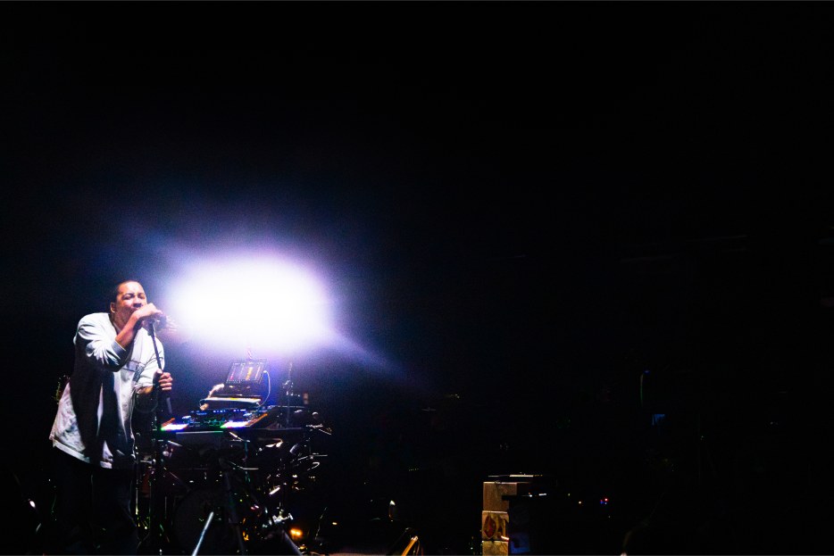 Dijon singing into a mic, a burst of white stage light beside him